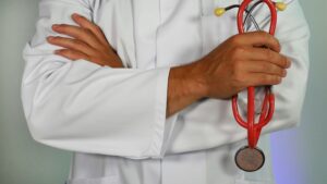 doctor holding a red stethoscope with arms folded